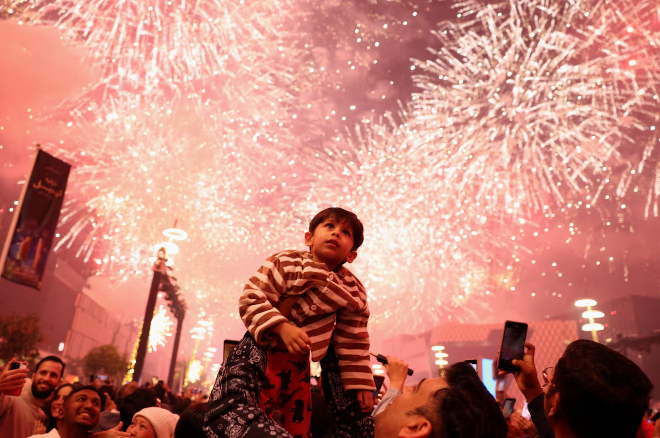 在卡塔尔卢赛尔，一名儿童抬头观看新年庆祝活动中绽放的烟花。路透社/穆罕默德·萨利姆 ... ... ... ... .. ...